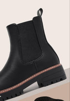 Black Chelsea boot side view showing elastic panel, contrast welt and lug sole