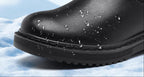 Close-up of black boot toe and lug sole with water droplets on the faux leather upper