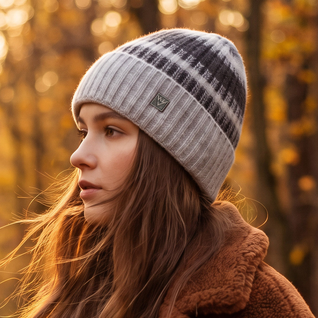 Striped knit beanie in light gray with dark stripes and small metal badge