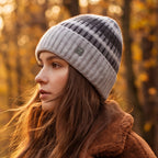 Striped knit beanie in light gray with dark stripes and small metal badge