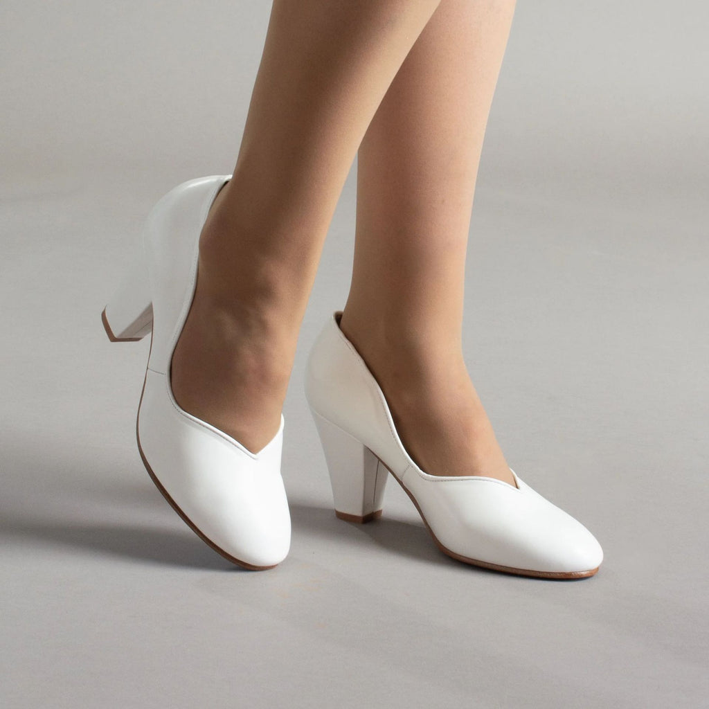 White leather pumps with closed toes, V-cut openings, and block heels
