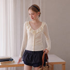 Cream knit cardigan with ruffle V-neck collar and button front, long fitted sleeves