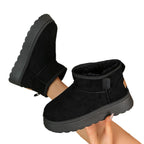 Women’s black suede short snow boots with ankle strap and thick, textured rubber sole