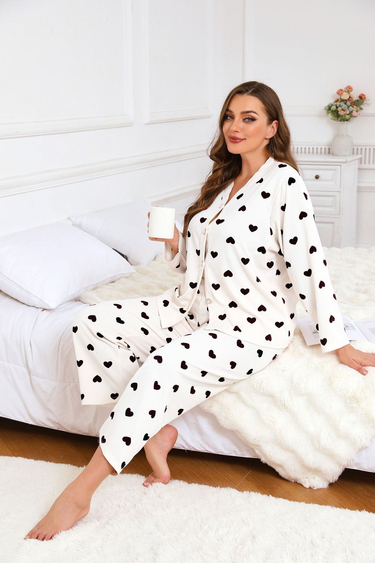 Women’s heart-print pajama set, white button-up top and pants with red hearts, lounging pose