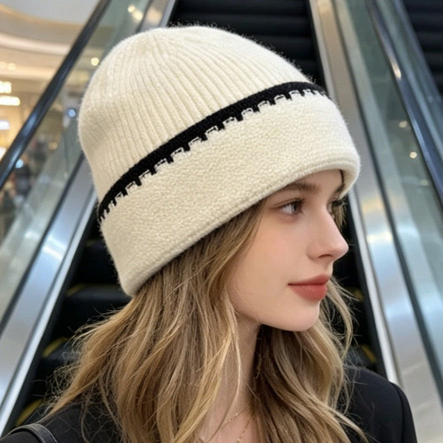 Ribbed knit beanie in off-white with black contrast stitch stripe at the cuff.