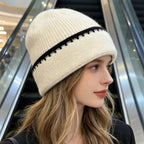 Ribbed knit beanie in off-white with black contrast stitch stripe at the cuff.