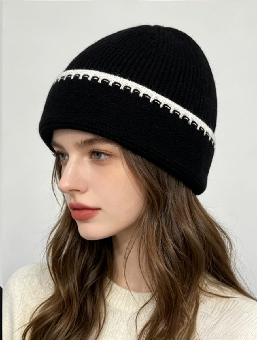 Ribbed knit beanie in black with white contrast stitch stripe at the cuff.