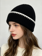 Ribbed knit beanie in black with white contrast stitch stripe at the cuff.