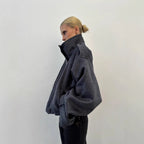 Dark gray cropped wool jacket, side view, funnel neck, button front, cuff tabs.