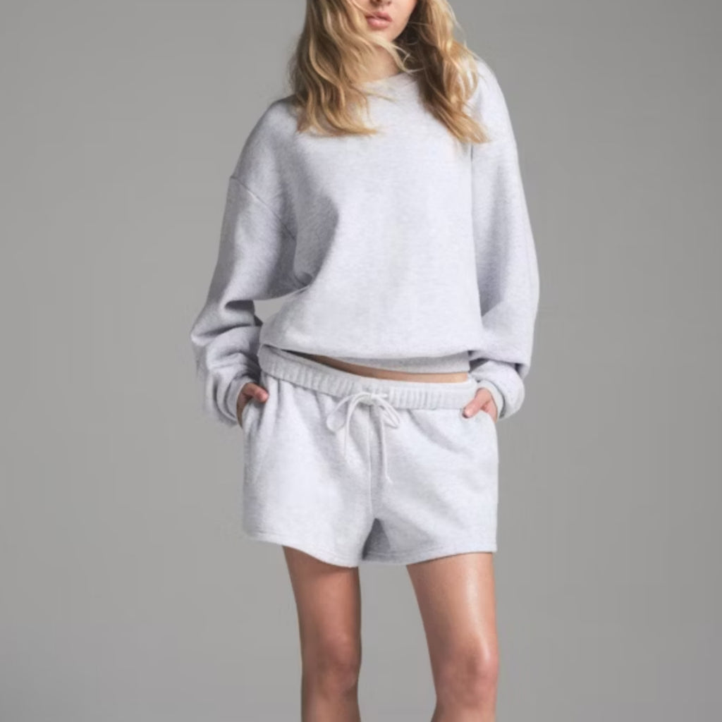 Light gray crew neck sweatshirt with matching drawstring lounge shorts, relaxed fit set.