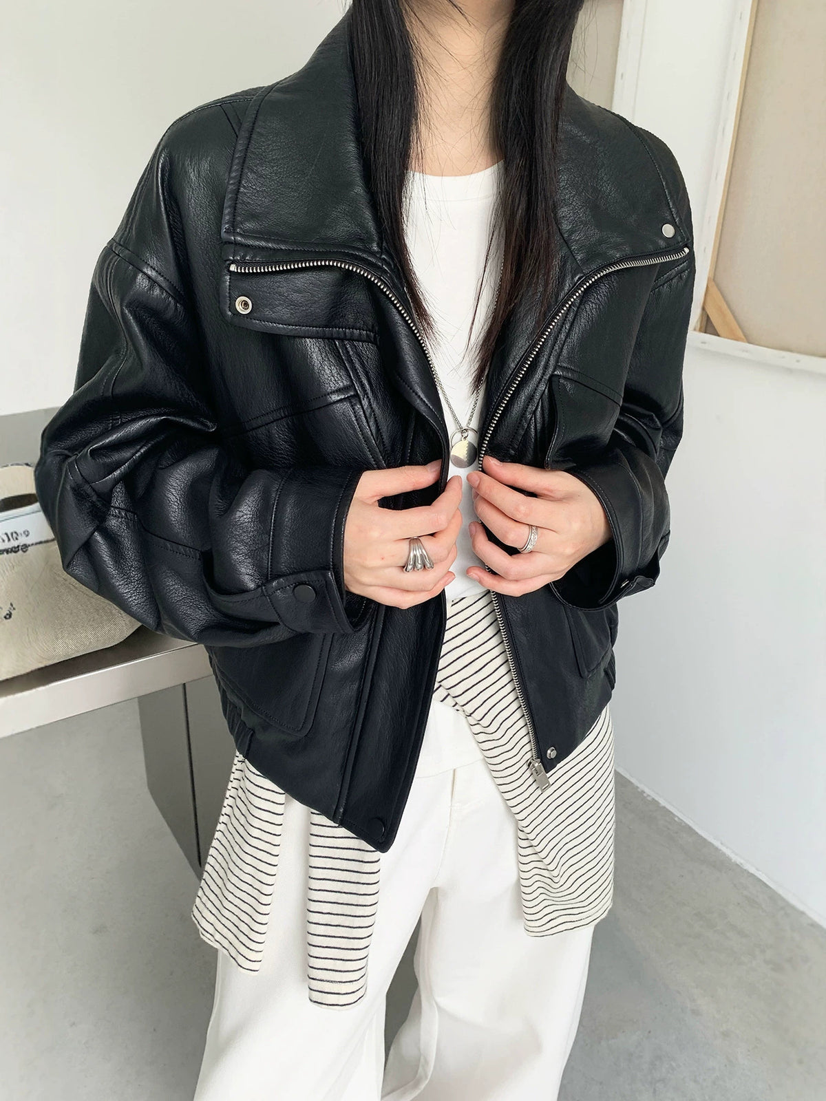 Cropped black faux leather jacket with stand collar and zip front, chest flap pockets