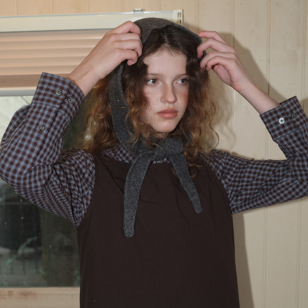 Dark gray wool knit skinny scarf with pointed ends, worn tied at the neck.