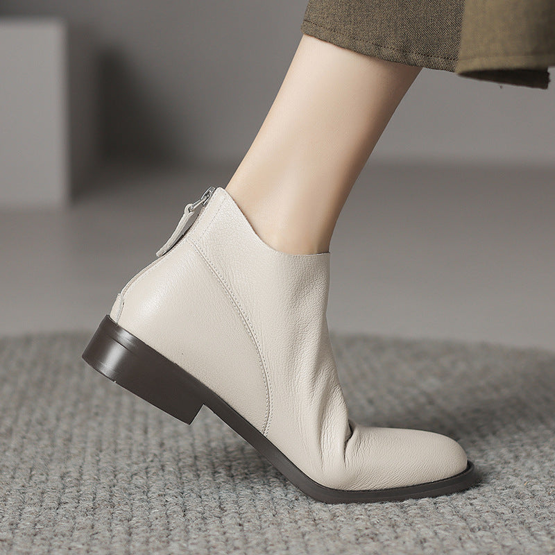 Off-white leather ankle boots with low block heel and back zip, side step view