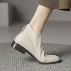 Off-white leather ankle boots with low block heel and back zip, side step view