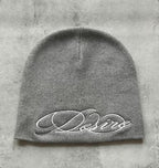 Gray knit beanie with white embroidered script lettering, flat lay front view.