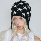 Black knit beanie with white star pattern and ear flaps, braided tie ends.