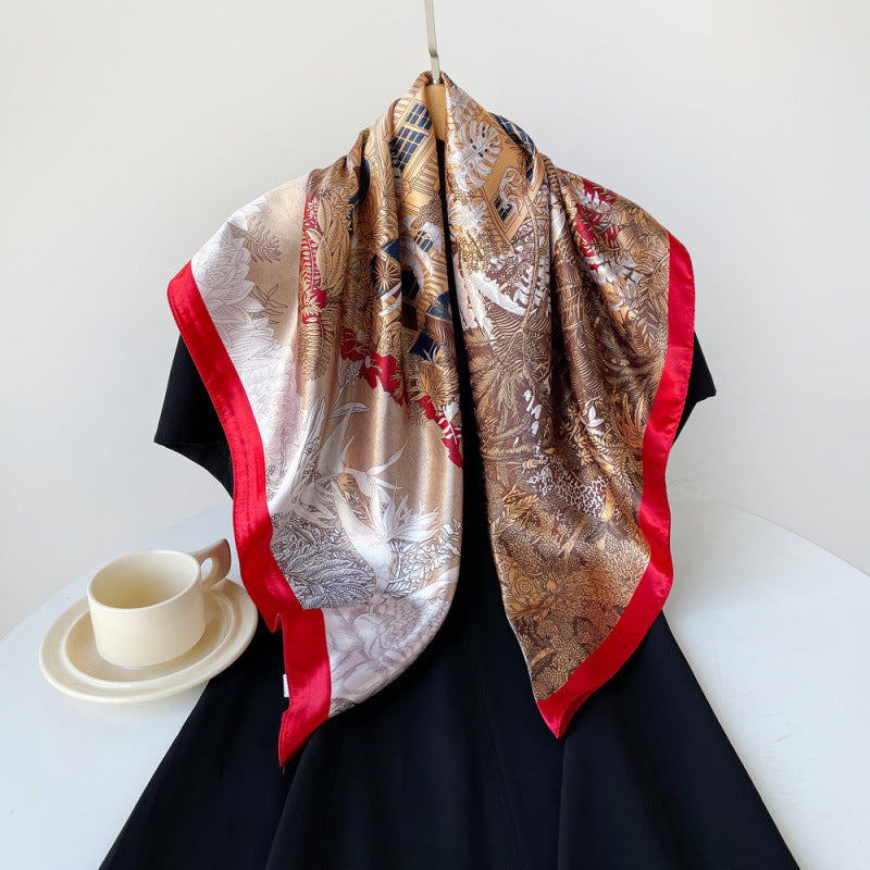 Camel satin square scarf with tropical pattern and red border, draped on black dress.
