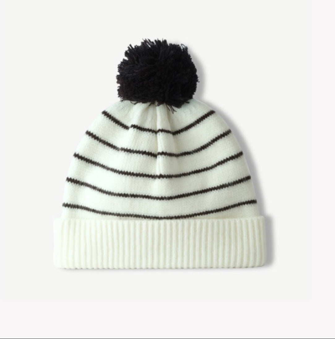 White-and-black striped knit beanie with fluffy black pom-pom and ribbed cuff