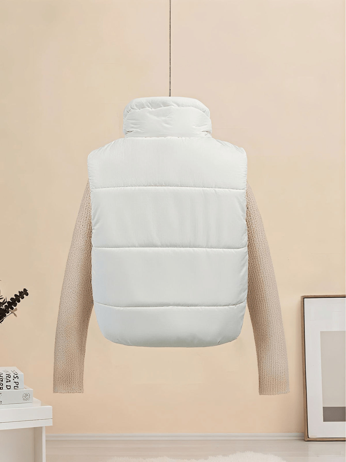 White sleeveless puffer vest with quilted horizontal baffles and stand collar.