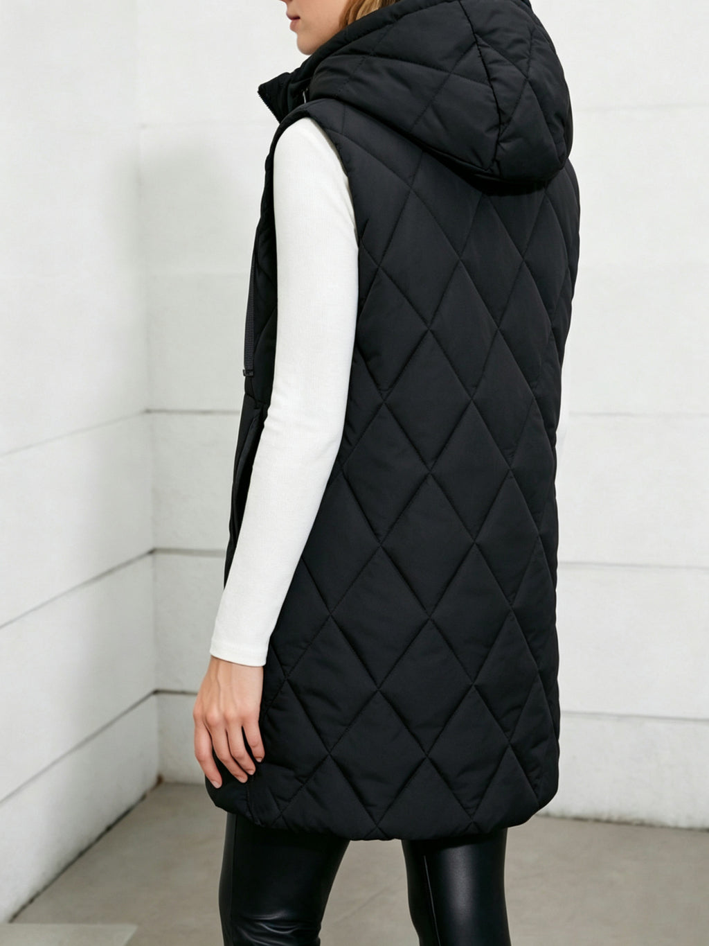 Black long quilted puffer vest with hood; diamond stitching and drawstring detail