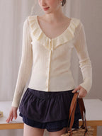 Cream knit cardigan with ruffle V-neck collar, button front, long sleeves