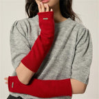 Red fingerless knit arm warmers with thumbhole and stitched label on cuff