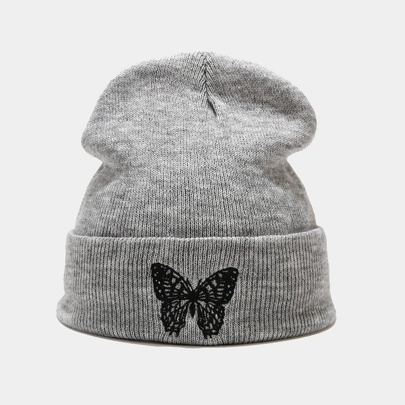 Light gray knitted beanie with black butterfly applique on front