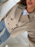 Khaki trench jacket close-up with double buttons, epaulet detail, and rolled cuffs