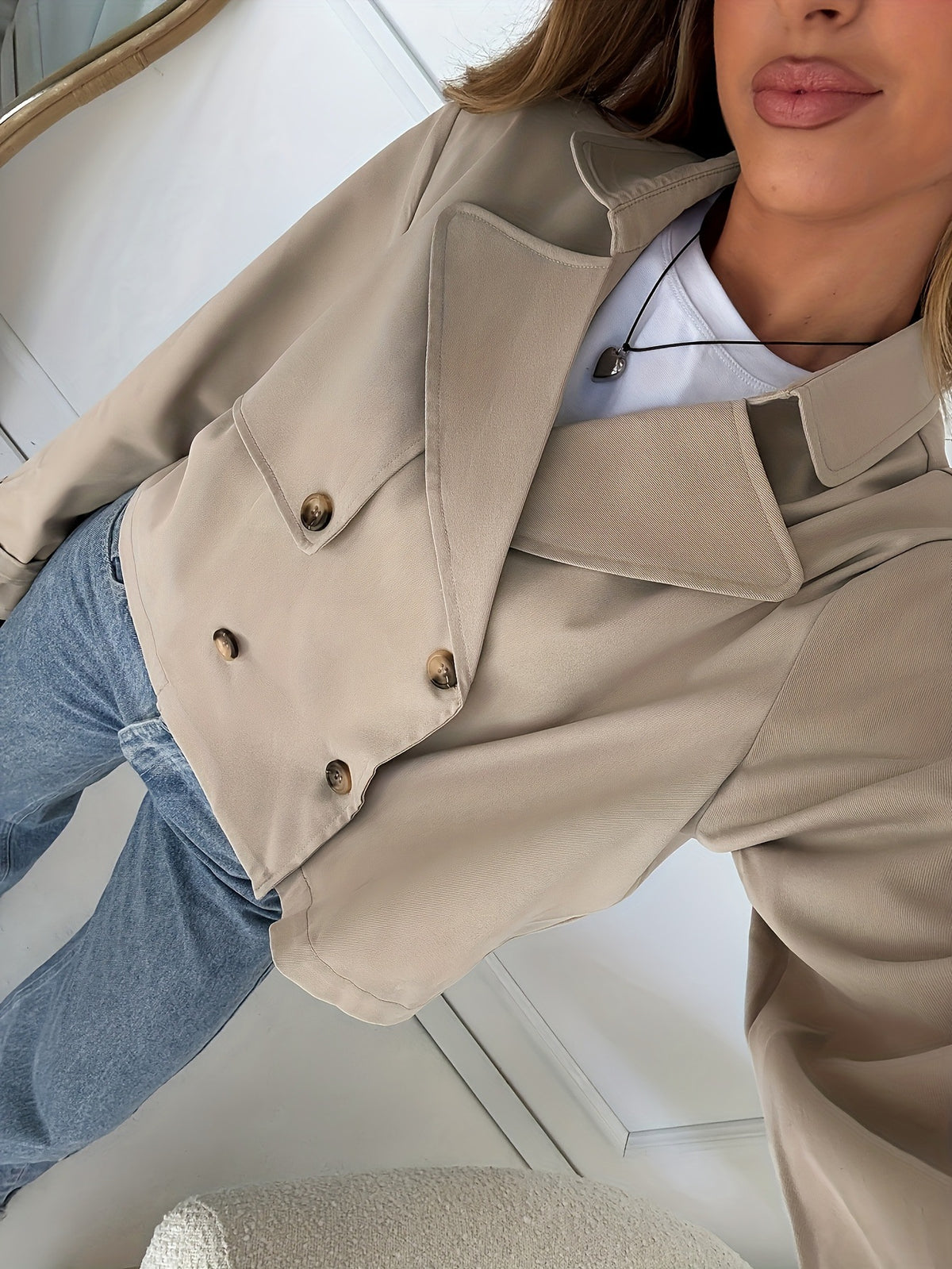 Khaki trench jacket close-up with double buttons, epaulet detail, and rolled cuffs