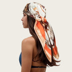 White satin square scarf head wrap with orange, gold, and brown chain paisley print