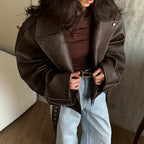 Brown moto jacket close-up with zip, snap buttons, and belted waist detail
