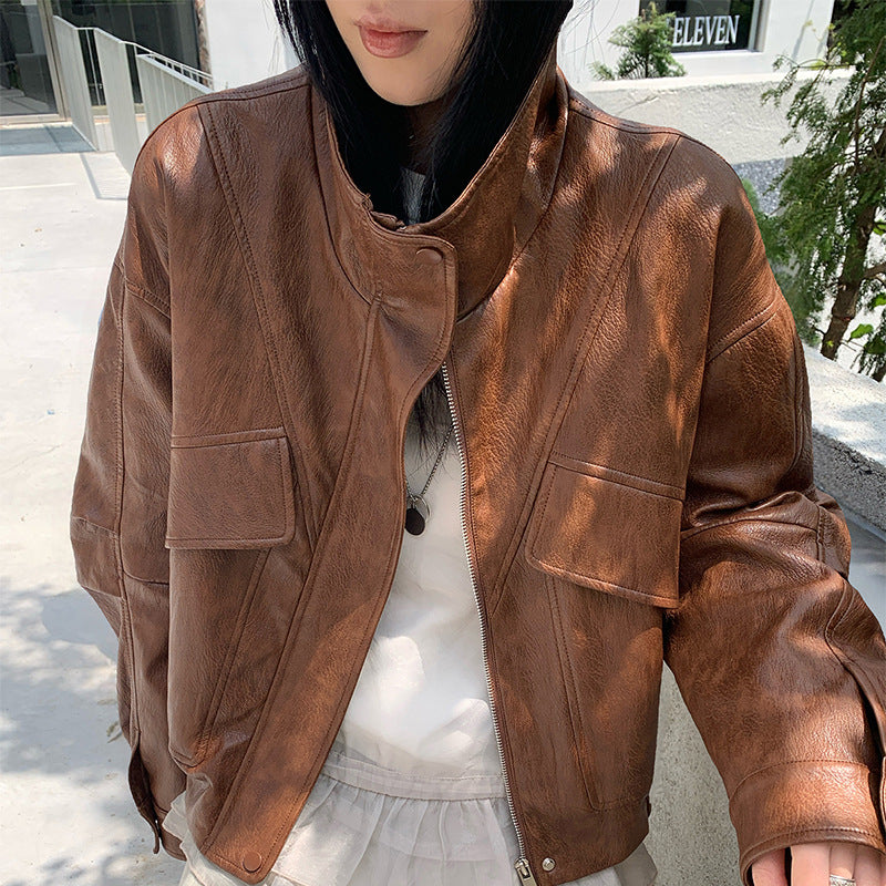 Cropped brown faux leather jacket with stand collar, zip front, and chest flap pockets