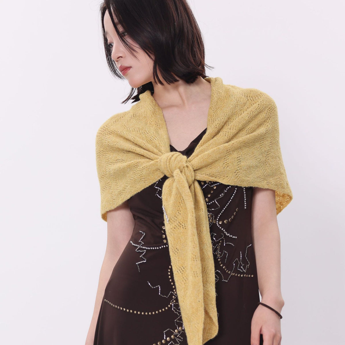 Mustard yellow knit triangle scarf worn tied over the shoulders
