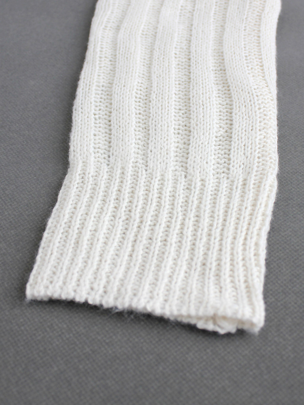 Off-white knit cardigan hem with ribbed trim and vertical pointelle texture