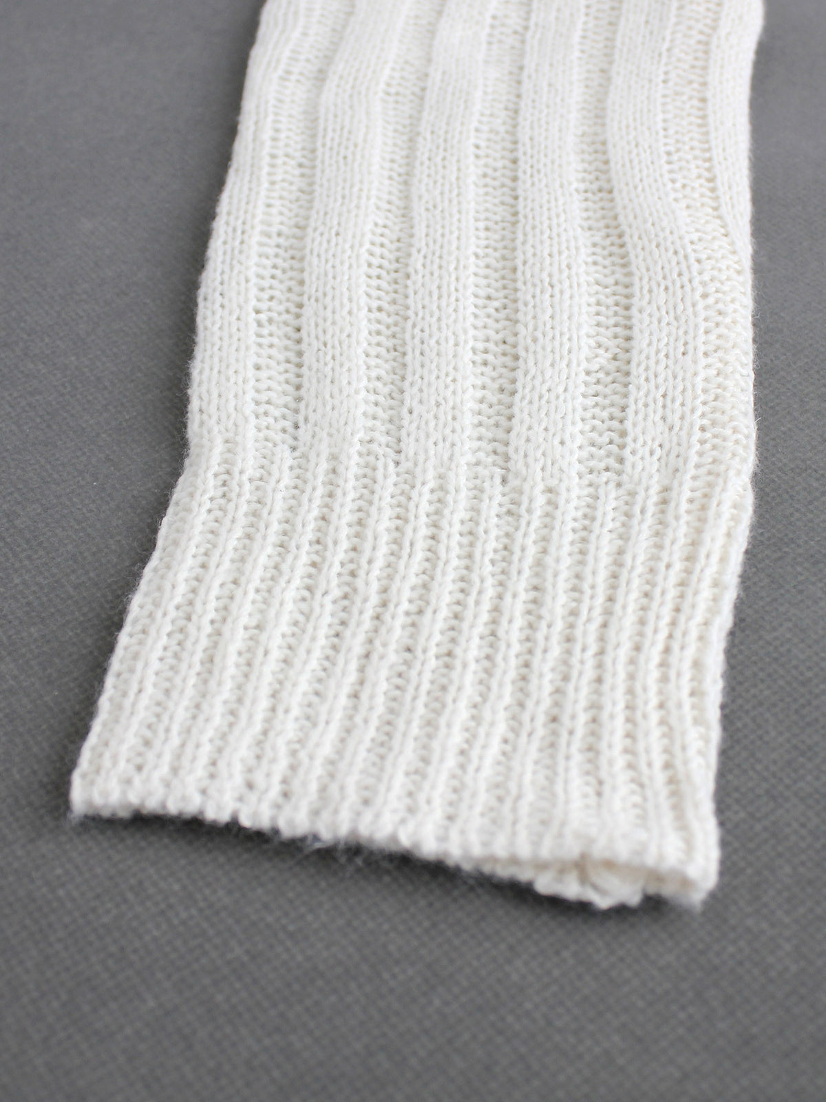 Off-white knit cardigan hem with ribbed trim and vertical pointelle texture