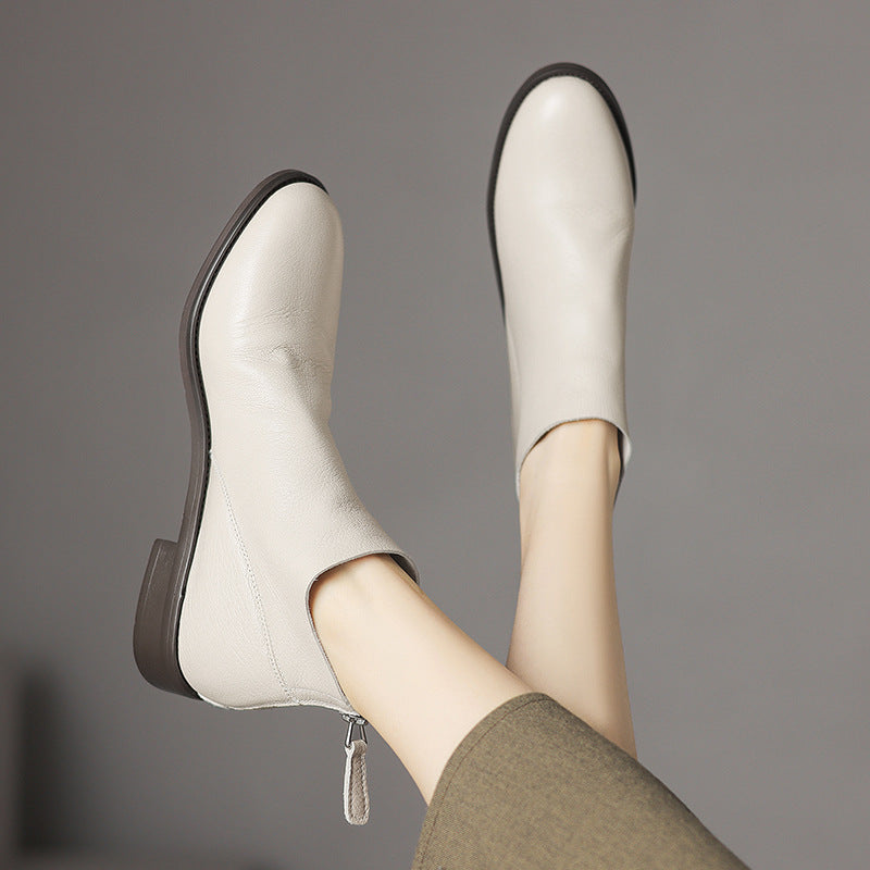 Off-white leather ankle boots with low block heel and back zip, pair angled view