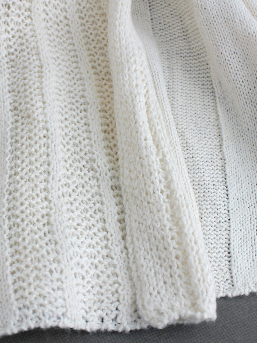 Off-white pointelle knit cardigan close-up with open-front drape panel texture