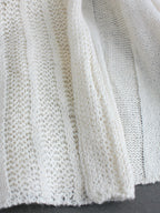 Off-white pointelle knit cardigan close-up with open-front drape panel texture
