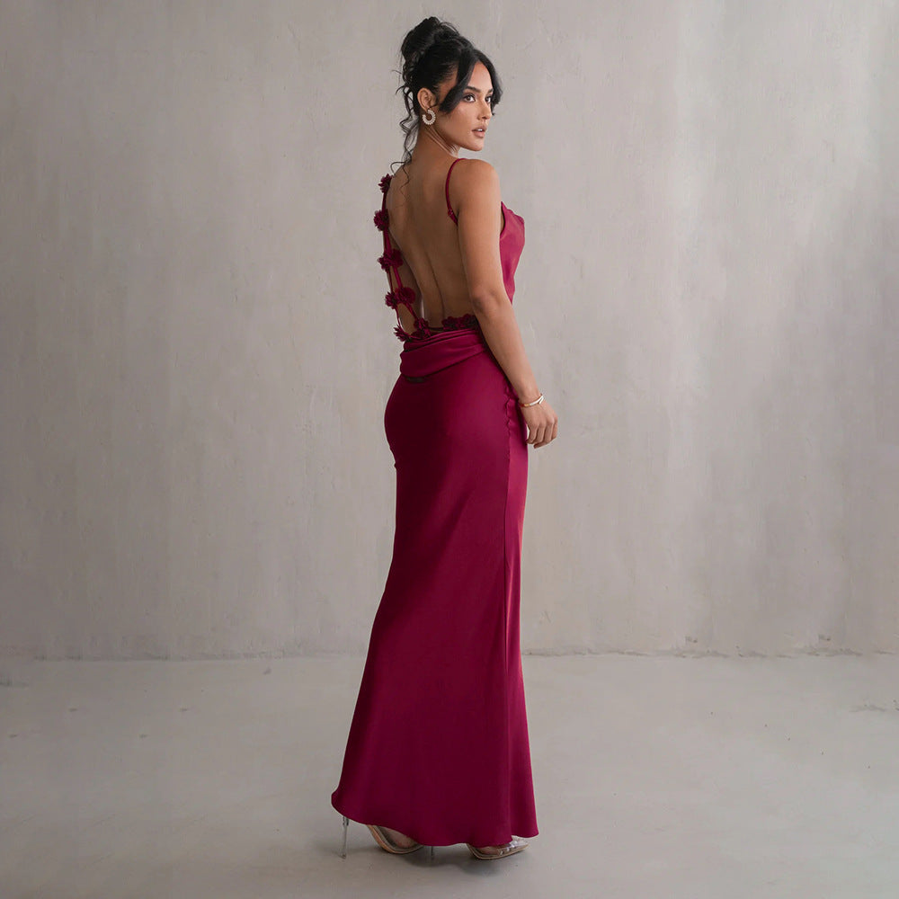 Burgundy satin maxi dress with backless open back and rosette strap detail.
