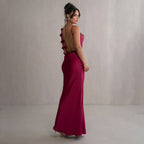 Burgundy satin maxi dress with backless open back and rosette strap detail.