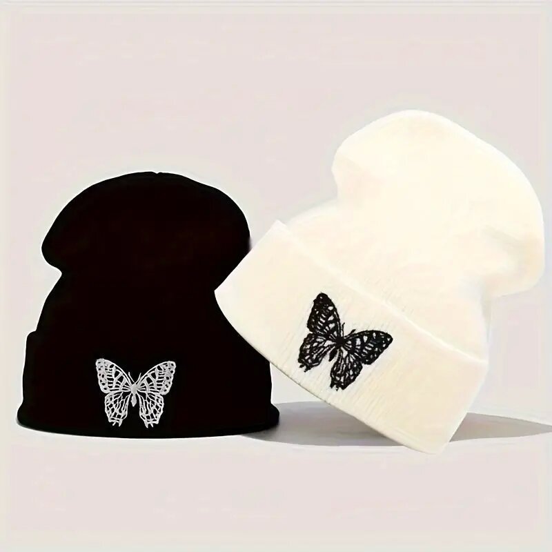 Two knit beanie hats: black and cream, each with black butterfly applique