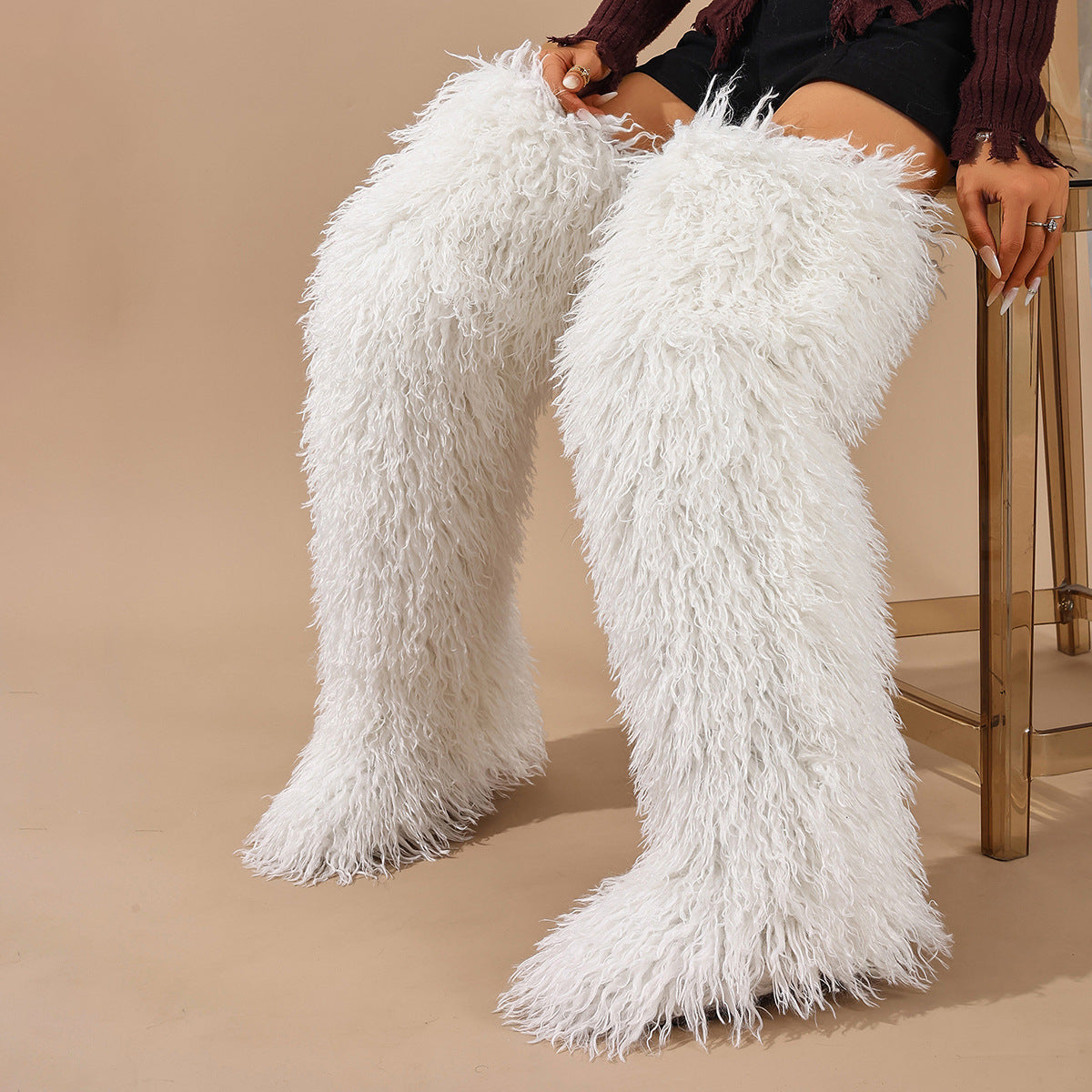 White shaggy faux fur thigh-high boots shown worn as a pair.