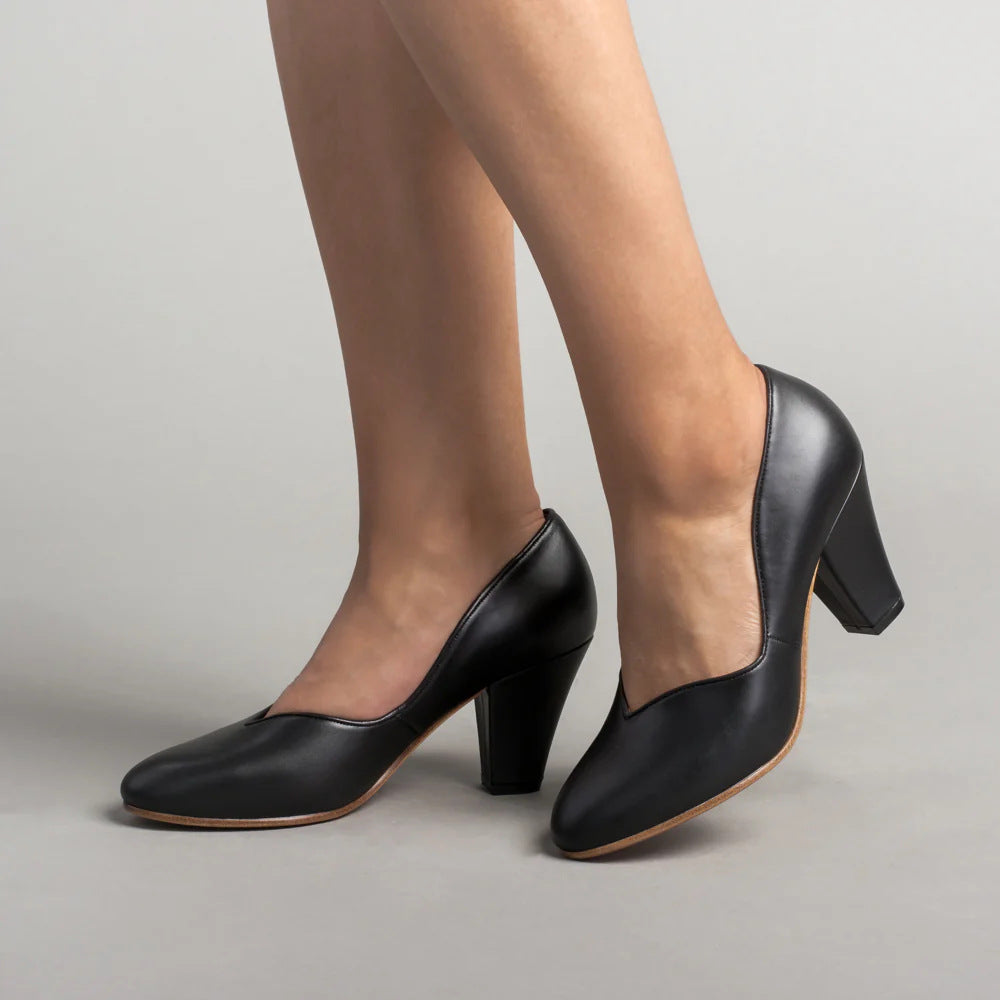 Black leather pumps in a side view, showing V-cut openings and block heels