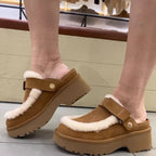 Tan-brown furry slip-on slippers with Velcro strap and thick sole, worn on feet.