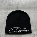 Black knit beanie with white embroidered script lettering, flat lay front view.