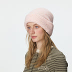 Speckled pale pink rib-knit beanie with a wide folded cuff, worn on a model.