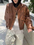 Cropped brown faux leather jacket with stand collar, zip front, and flap pockets