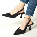Black tweed slingback pumps with pointed toe and flared heel, ankle chain strap
