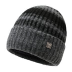 Striped knit beanie in dark charcoal gray with light pattern and metal badge