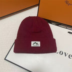 Burgundy ribbed knit beanie with folded cuff and woven brand patch.